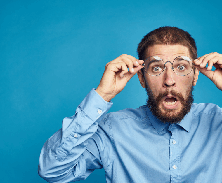 Überraschter Mann mit Brille- symbolisch für unerwartete Fehler beim Hausverkauf, die Eigentümer vermeiden sollten