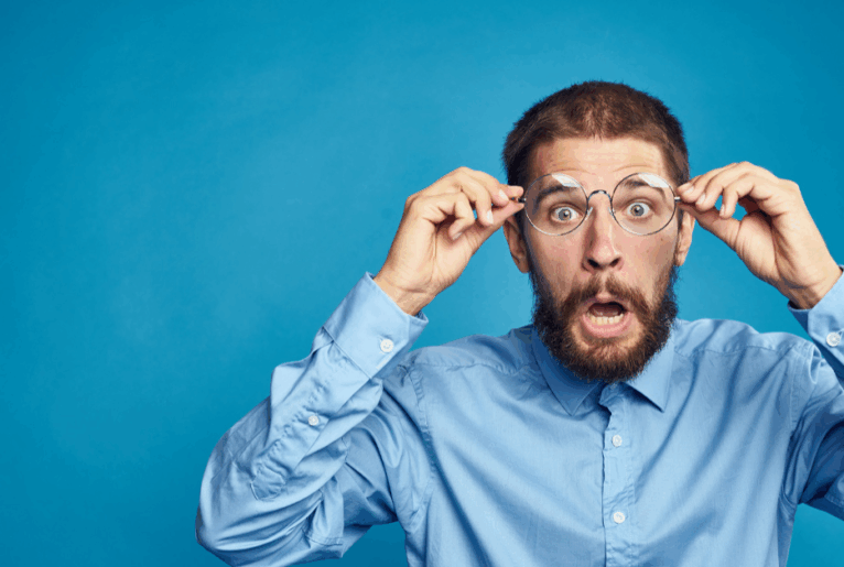 Überraschter Mann mit Brille- symbolisch für unerwartete Fehler beim Hausverkauf, die Eigentümer vermeiden sollten